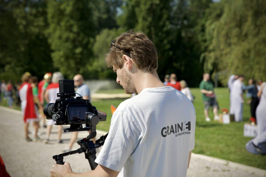 Caméraman de Graine de Production en plein tournage du teambuilding romain de CPMS, capturant les moments forts de l'événement en extérieur.